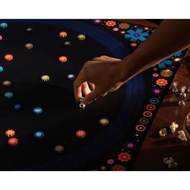 Main jouant avec des perles colorées lumineuses sur tissu noir